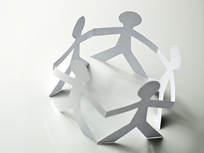 White paper cutout of figures joined at hands standing in a ring