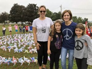 Students and teachers with peace message t-shirts with pinwheel installation in background