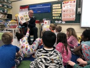 Superintendent smiling with book, reading to children
