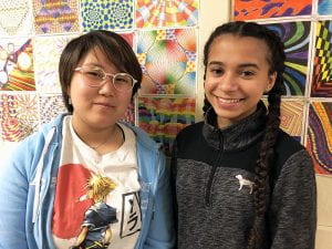 Two student artists with artwork in background