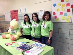 School social workers and Family Engagement coordinator wearing green mental health awareness t-shirts at informational table
