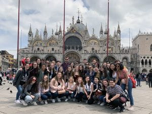 Group of students posed in St. Marks Square, Venice with basilica in background