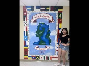 Female student standing next to world cultures wall mural