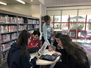 Library Media Specialist Patty Eyer works with group of students in TZHS Library