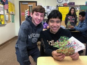 Two students smiling, with one holding wrapped gift