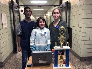 Three students in hallway with cash box and trophy