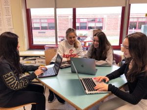 TZHS teacher Karen Connell working with three female students on laptops