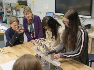 Teacher and students looking at bridge and structure tester