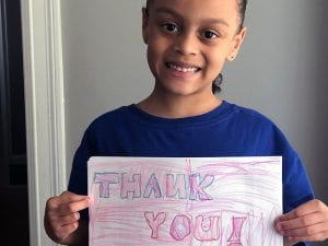 Student smiling with "thank you" sign