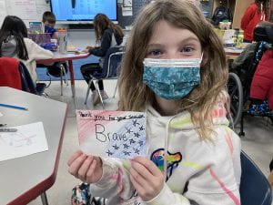 Fifth-grade student holding "thank you" message for veteran