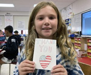 Student holding handmade Veterans Day thank you card