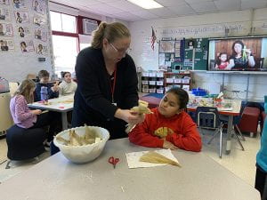 Literacy Coach Kristy Nadler helps student make corn husk doll