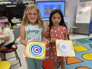 WOS art students hold concentric circles paintings